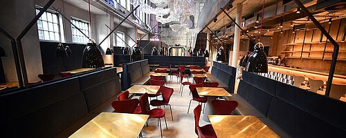 Tische mit Stühlen im Ofenhaus im Gaswerk. Weiterverlinkung auf German Design Award 2020 Newsartikel