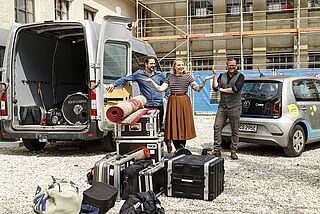 Eine Frau und zwei Männer mit Musik-Equipment vor einem swa-Carsharing-Auto. - Beim anklicken wird das Bild vergrößert.