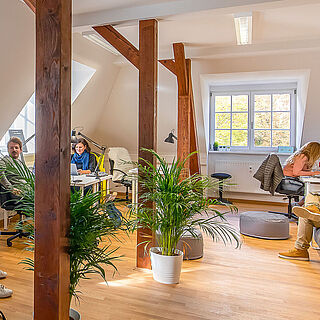 Mann sitzt auf einer Bühne an einem Klavier. Vor ihm sind aufsteigende Plätze auf denen Menschen sitzen. Weiterverlinkung auf Gaswerk kreative Arbeit Seite