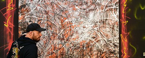 Person steht vor einem Kunstwerk. Weiterverlinkung auf URBAN LOVESTORY Newsartikel