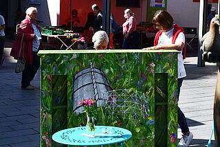 Frau spielt auf bemalten Klavier, eine weitere Dame hört zu. - Beim anklicken wird das Bild vergrößert.