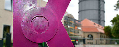 Pinke Kunstskulptur in Form eines K vor dem Gaswerk. Weiterverlinkung auf Bayerischer Staatspreis für Kreativorte Newsartikel