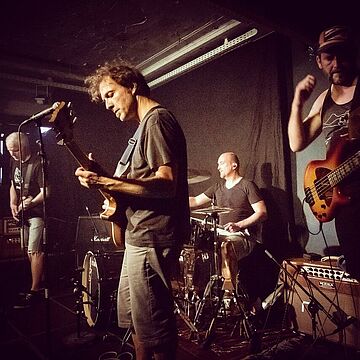 Vier Personen mit Instrumenten auf einer Bühne - Cover von calmer than you