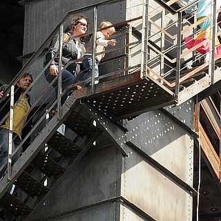 Gäste lauf die Treppen zum Aufstieg des Gaskessels im Gaswerk hinauf. Weiterverlinkung auf Gaswerk erleben Seite