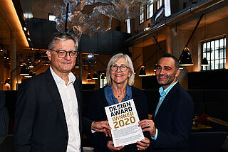 Drei Personen stehen im Ofenhaus und halten eine