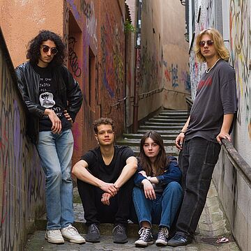 Vier Personen posieren in einer Seitengasse - Cover von Rainy Monday