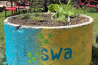 angemalter Betonkübel, welcher bepflanzt wurde. - Beim anklicken wird das Bild vergrößert.