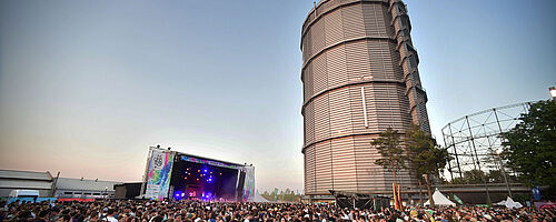 Menschenmenge auf dem Gaswerk beim Modular Festival. Im Hintergrund ist eine Bühne und der große Gasbehälter. Weiterverlinkung auf Modular 2023 Newsartikel